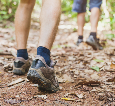 Close up of hiking boots walking on a dirt path.