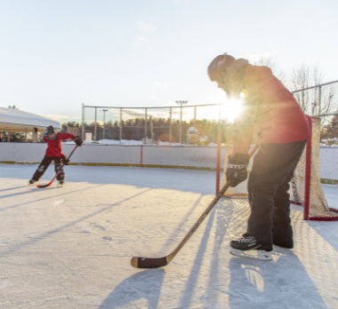Image of two people playing outdoor hockey in the winter.