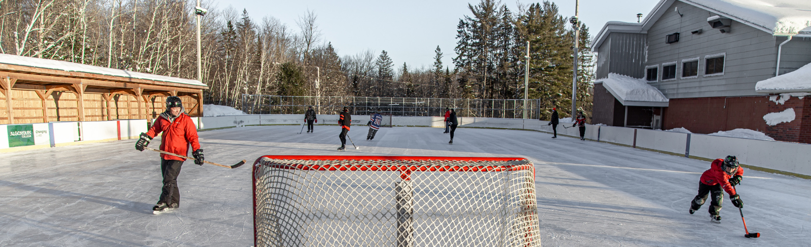 A group of people playing hockey on an outdoor rink.