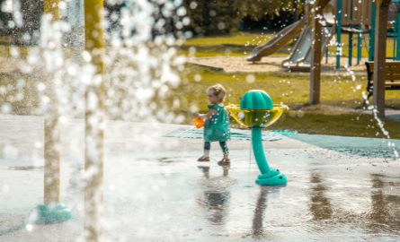 A little girl playing at a splash pad.