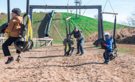 A group of people playing on the play structure at Hugli's.