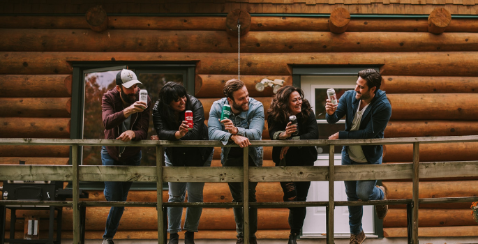 A group of people hanging out on a balcony drinking beer from a can.