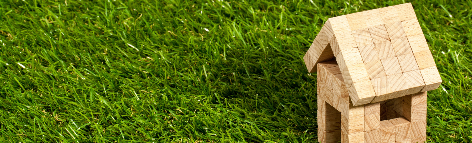 Miniature wood house on green grass.