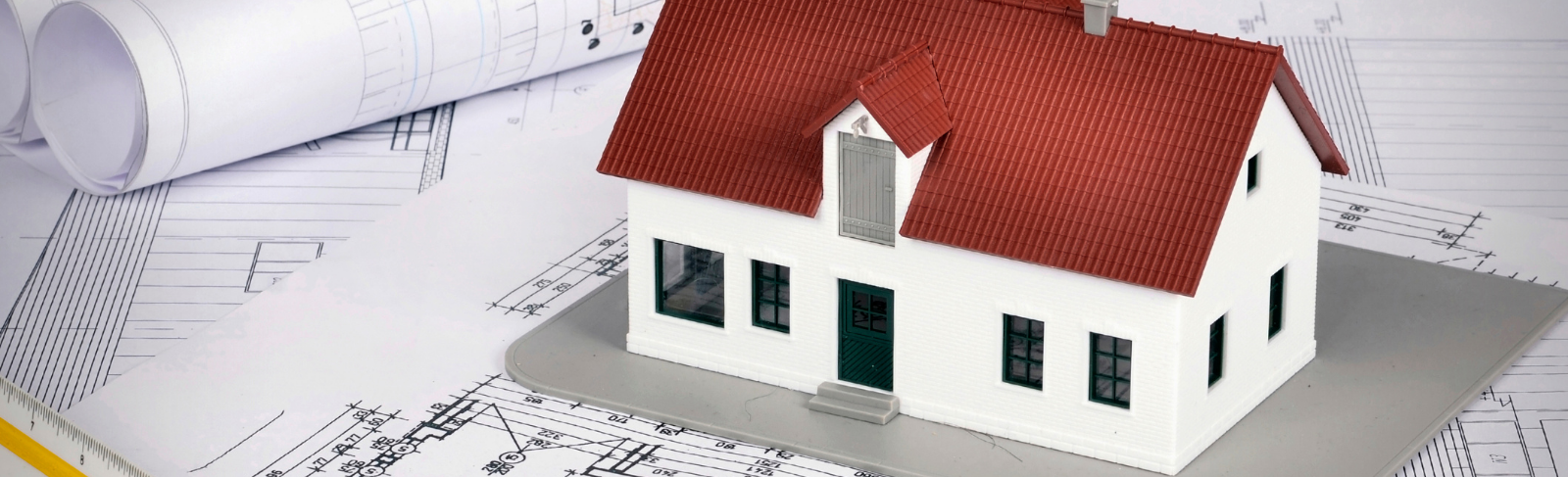 A miniature house on a pile of draft papers. 