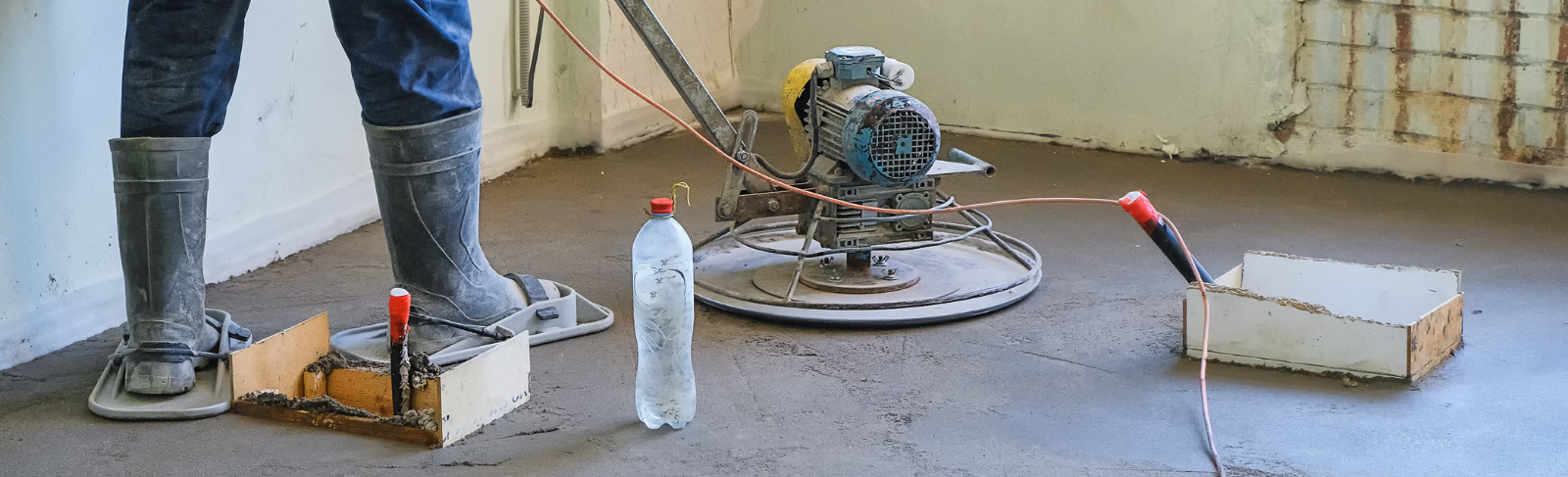 A worker laying concrete flooring and buffing it. 