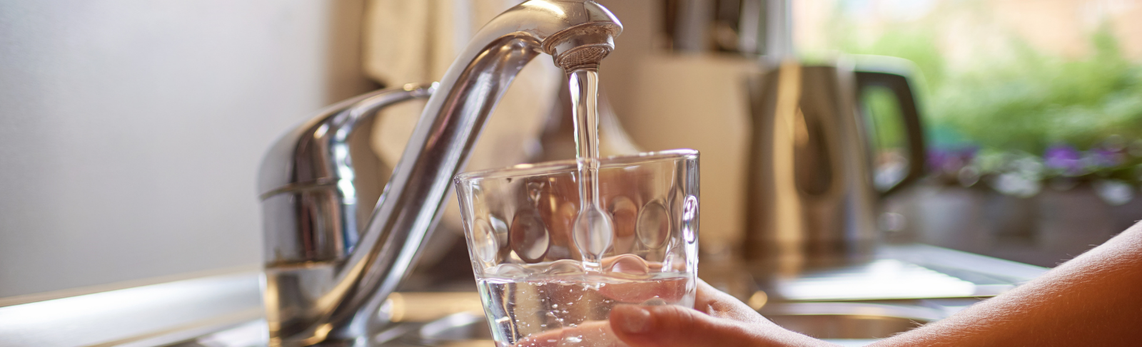 Water flowing out of a tap into a glass.