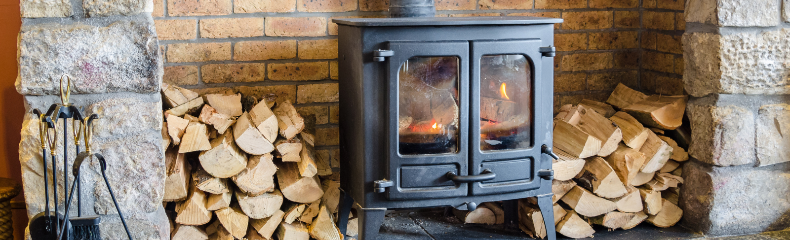 Indoor wood fireplace with piles of wood on either side. 