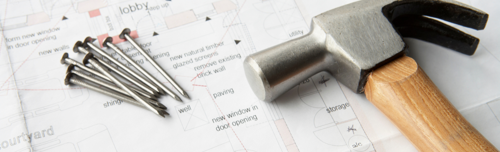 Hammer and nails on top of drafting plans.