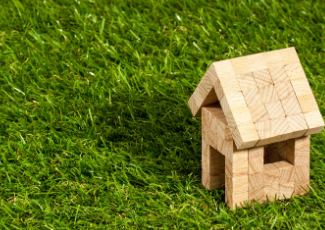 A miniature wood house on grass.