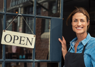 A woman opening a door to a business with an open sign.