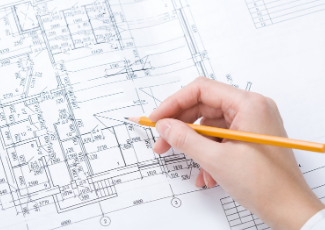 A hand holding a pencil looking at a draft plan.