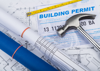 Rolls of plans and a hammer laid out on a table.