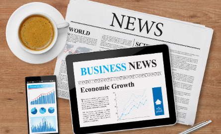 Aerial shot of a newspaper, ipad, and coffee mug with the words news.