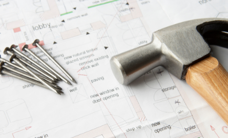 Hammer and nails on top of drafting plans.