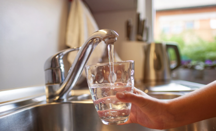 Water flowing out of a tap into a glass.