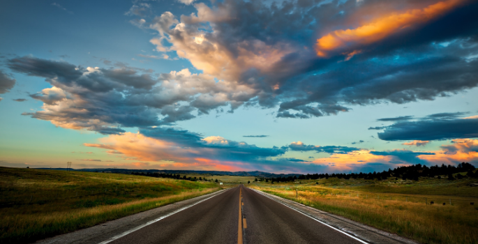 Open highway with a cloudy sunset sky.
