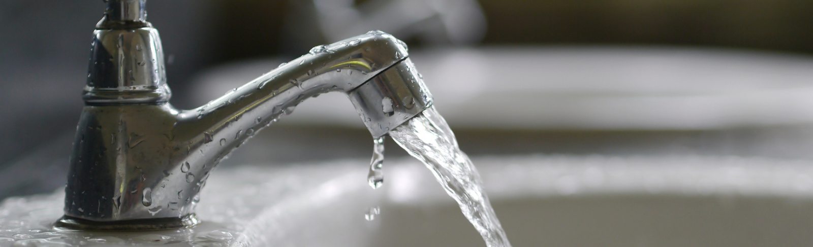 An open sink faucet with water pouring out.