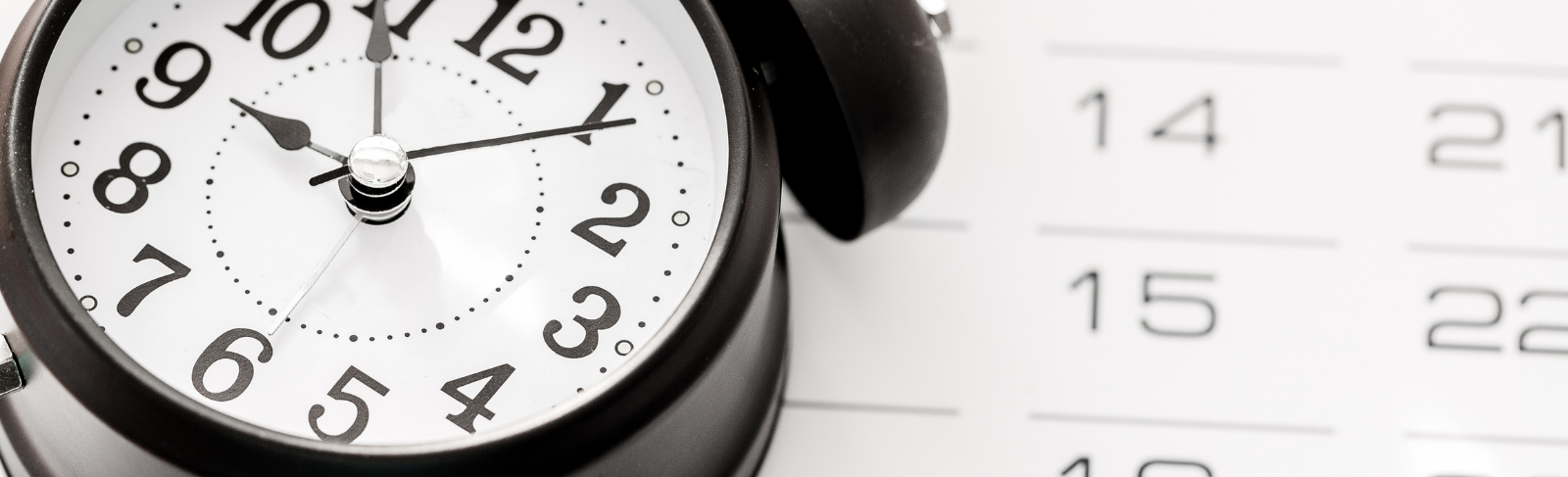 A calendar with an alarm clock on top.