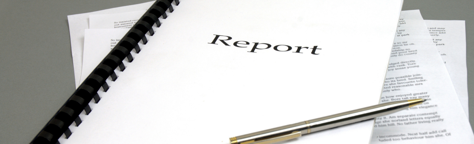 A report folder on a table with a pen.