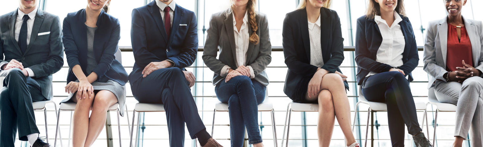 A group of people sitting in a row wearing corporate attire.