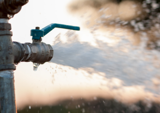 An open water main with water gushing out.