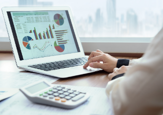 A person working on a laptop that has graphs and charts on the screen.