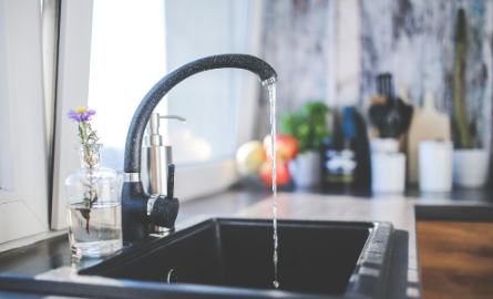 An open sink faucet with water pouring out.