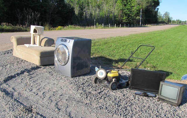 Photo of large items out for collection organized in a line at the end of a driveway divided by item type. 