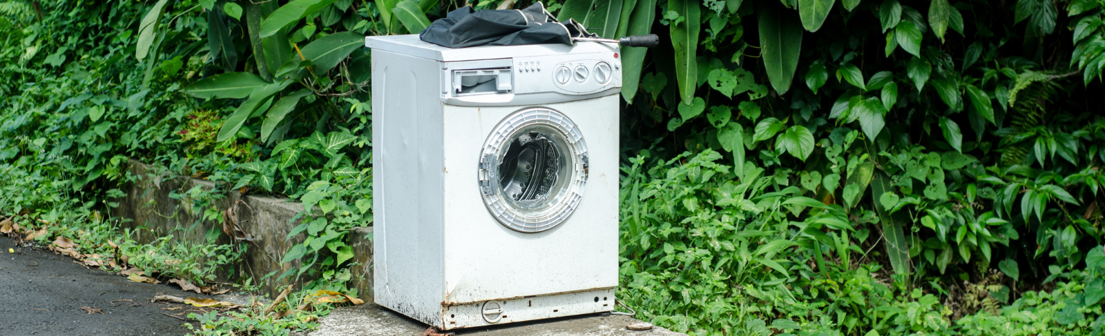 Washing machine outside on a road for large item collection.