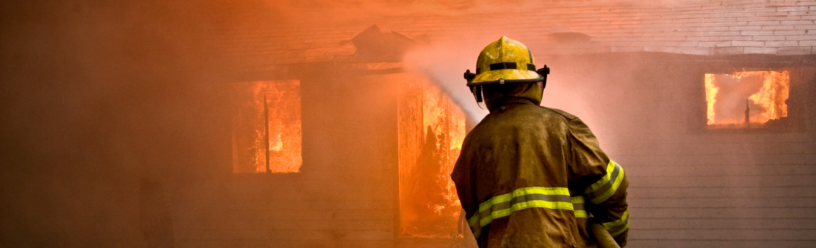 A firefighter fighting a house in flames.