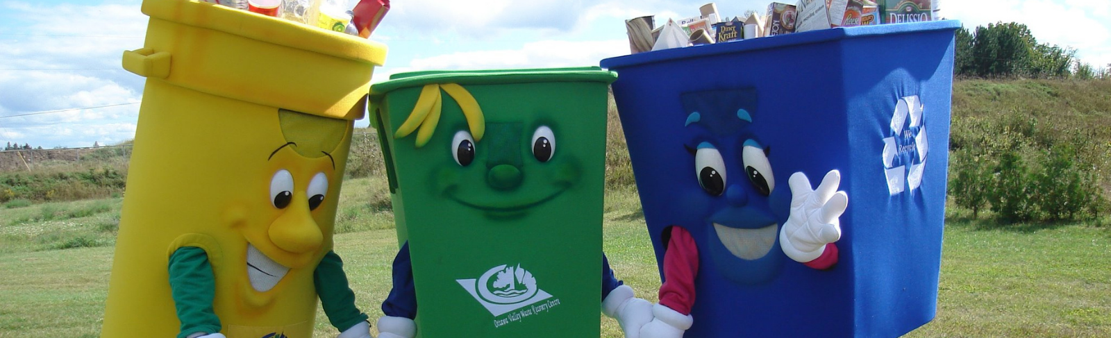 3 human sized mascots of a green bin, yellow recycling bin, and blue bin. 