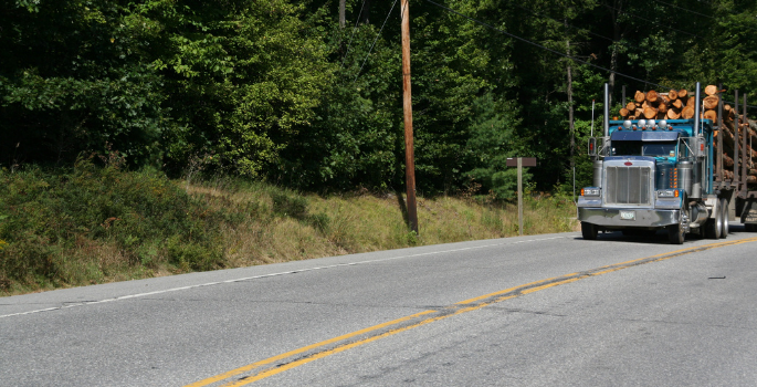 Logging truck driving on a paved road.