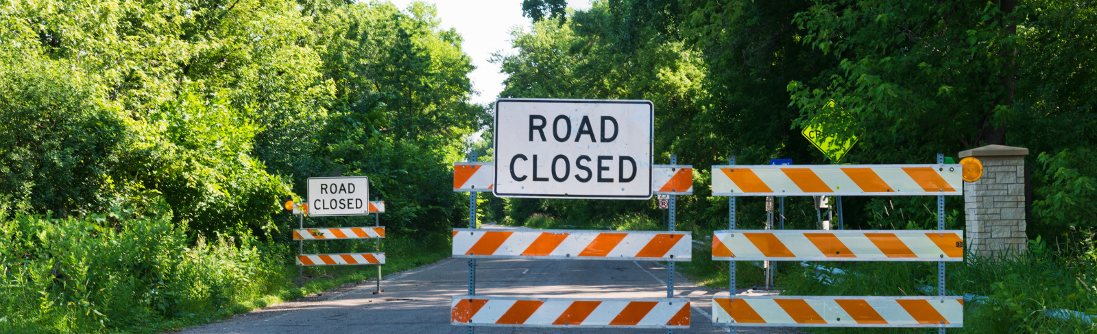 Road closed sign with barricades blocking a road.